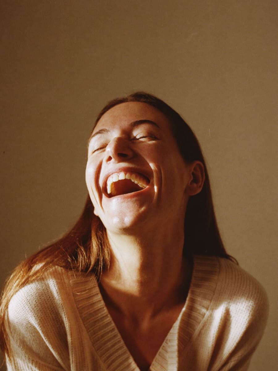 Woman laughing in cream knit sweater